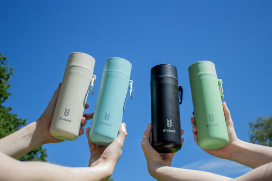 Blue sky with 4 reusable water bottles held up including oat bottle, blue bottle, black bottle and green bottle