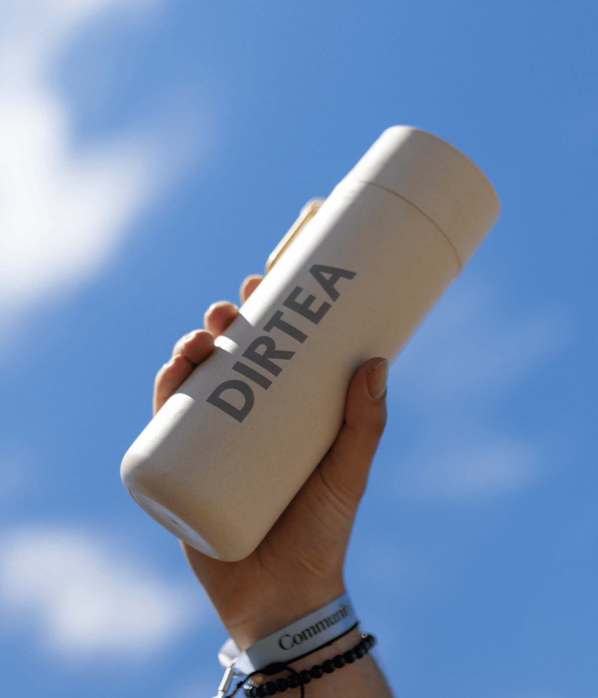 Dirtea drinks bottle in oat colour held up to sky