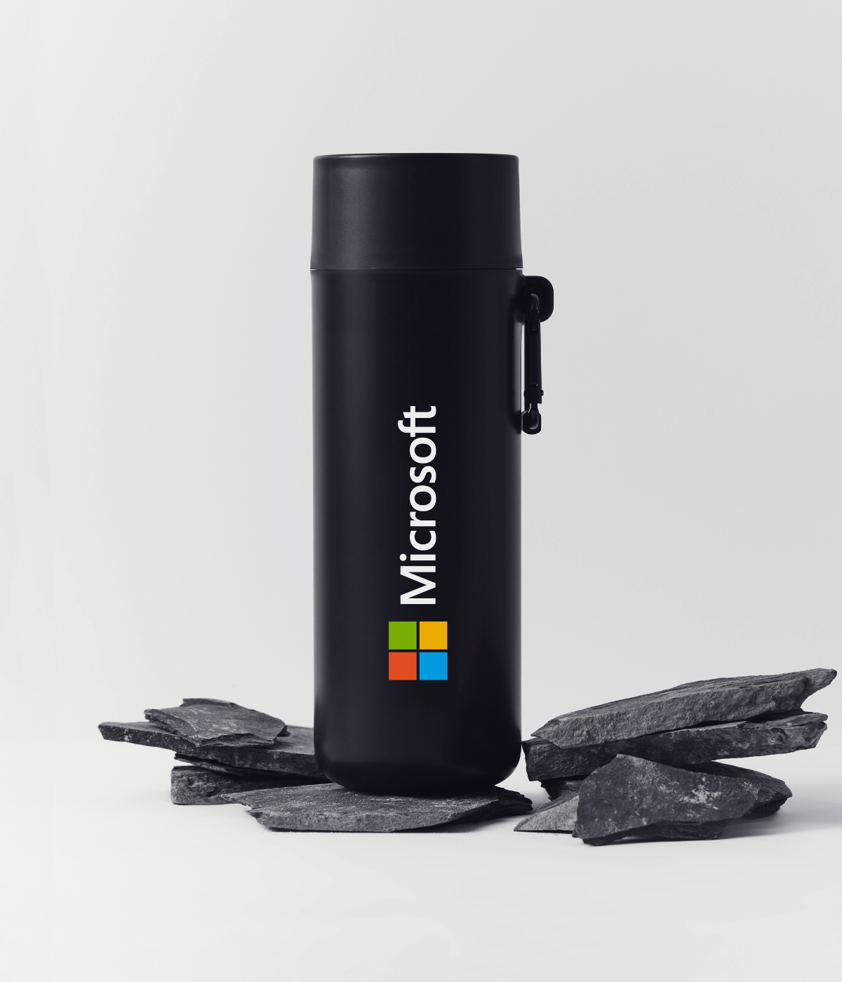 Black reusable bottle with custom logo beside stones